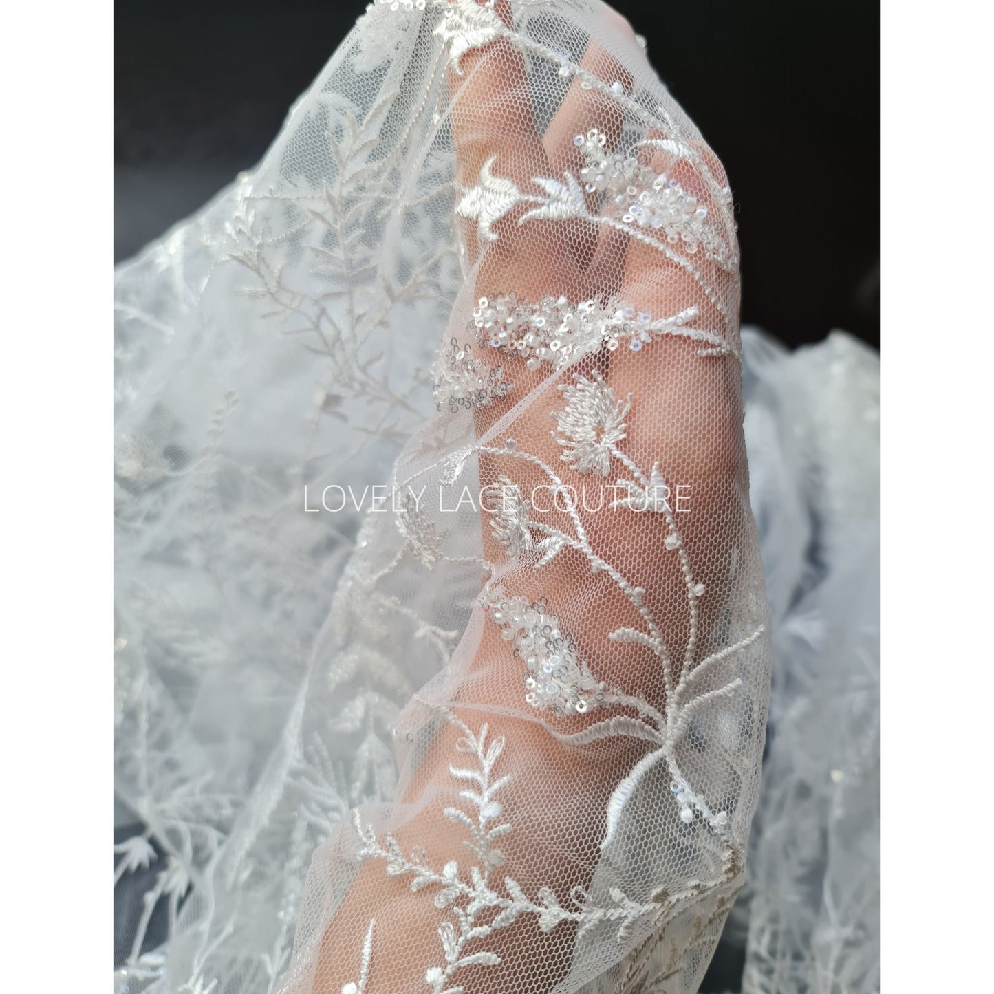 lace fabric with transparent buggle beads and sequins in white color, closer picture of the design shown onhand