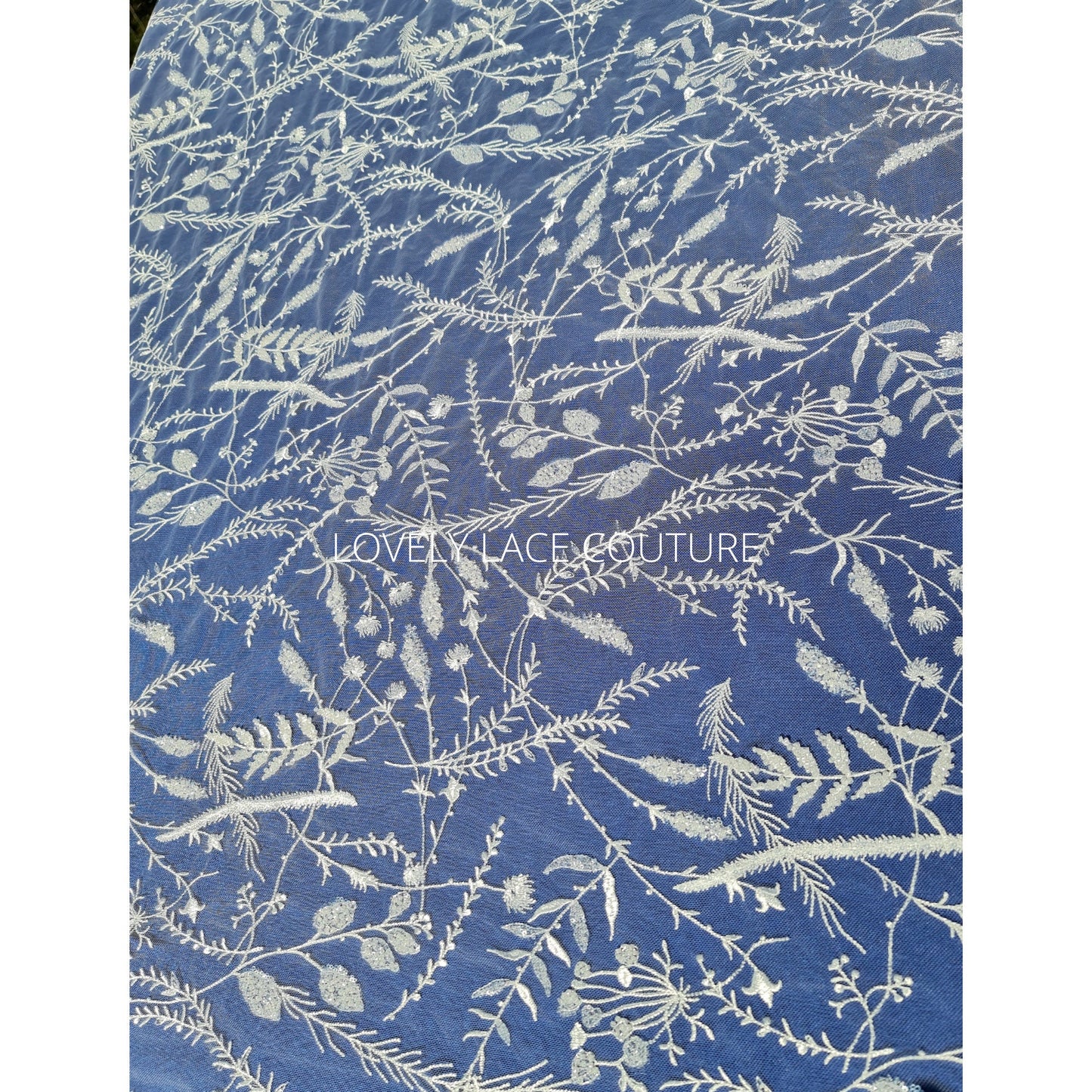 lace fabric with transparent buggle beads and sequins in white color on a blue background