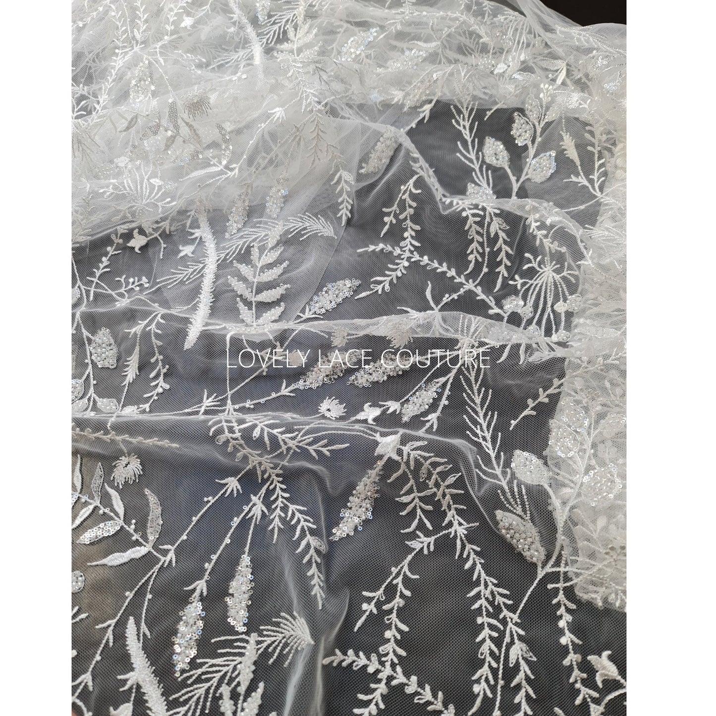 lace fabric with transparent buggle beads and sequins in white color, closer picture of the design shown on a black background