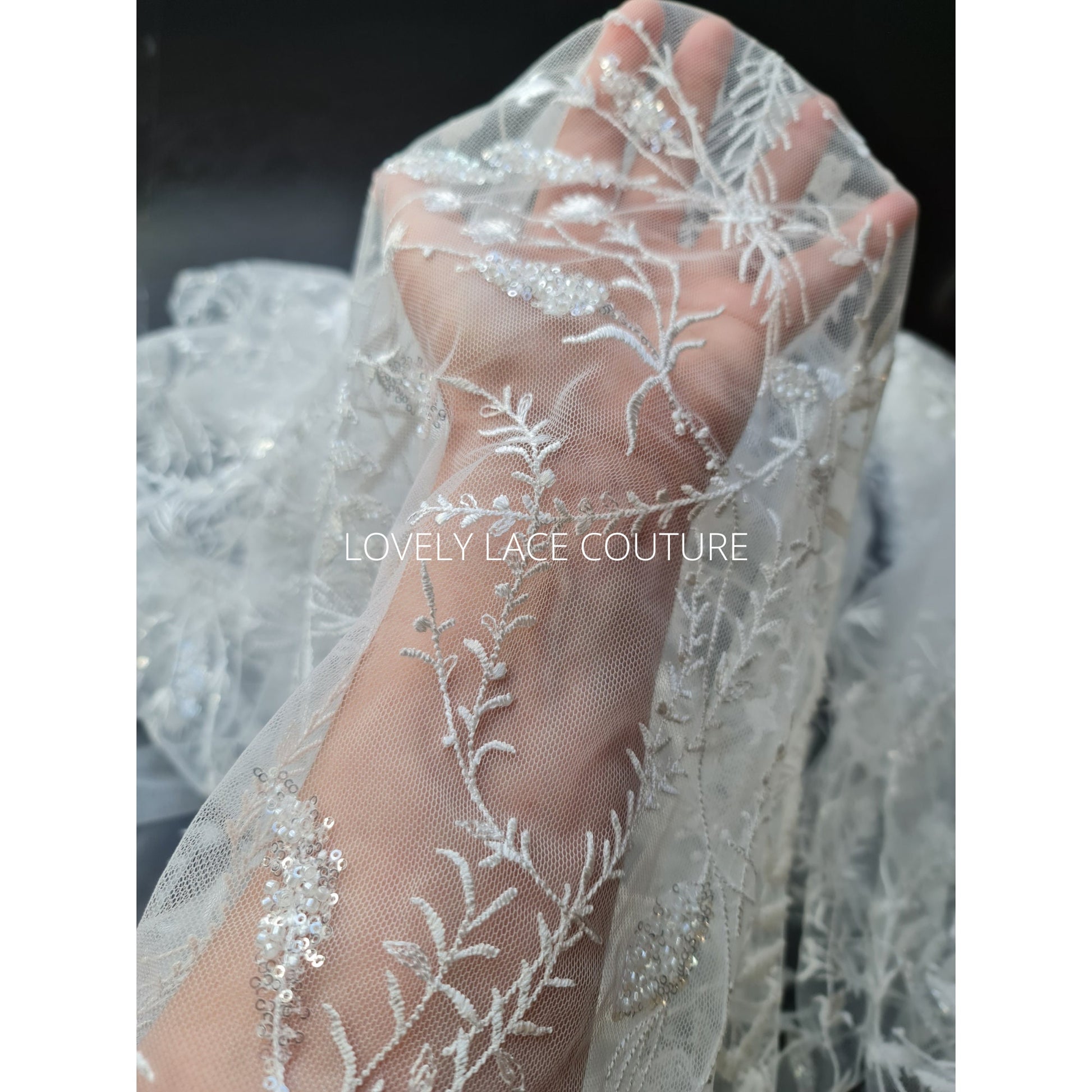 lace fabric with transparent buggle beads and sequins in white color, closer picture of the design shown on hand