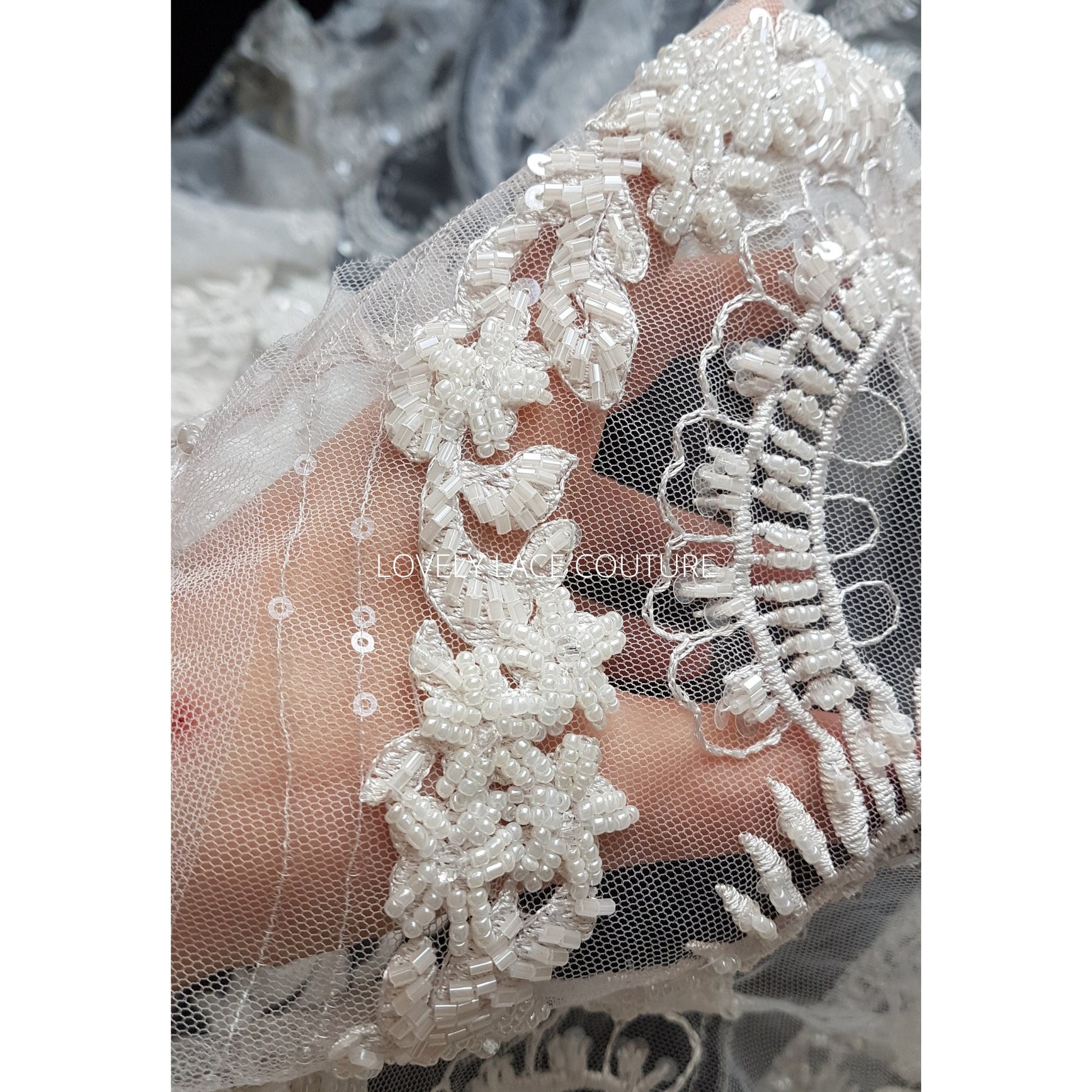 lace fabric with beads and sequins shown on hand